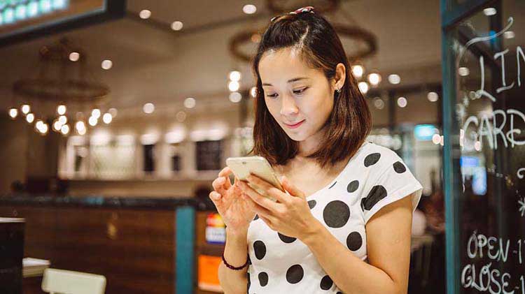 Woman looking at smartphone and accessing her files stored in the cloud.