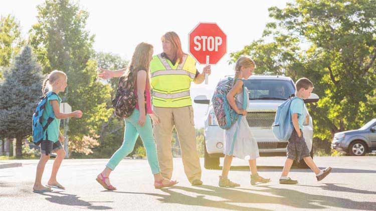 Mother and daughter practice pedestrian safety when crossing the street.