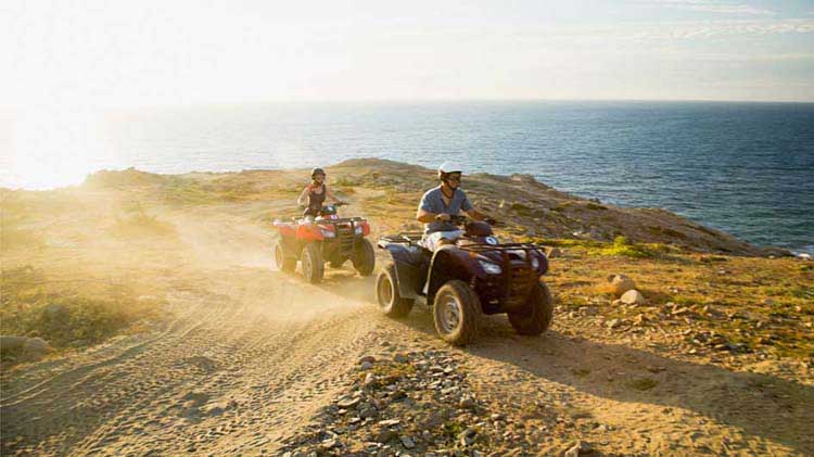 People riding on ATVs with ATV safety gear.