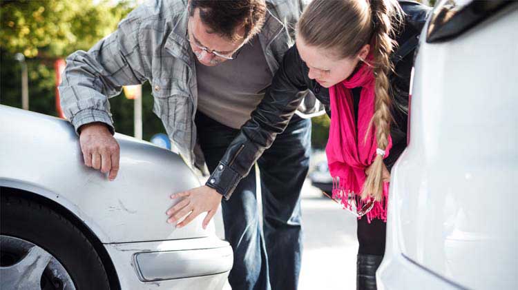 People looking at scratches on a car resulting from a car accident.