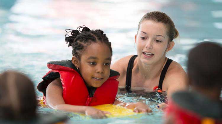 A young girl taking swimming lessons.