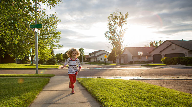 Child running in a neighborhood made safer by neighborhood social media network.