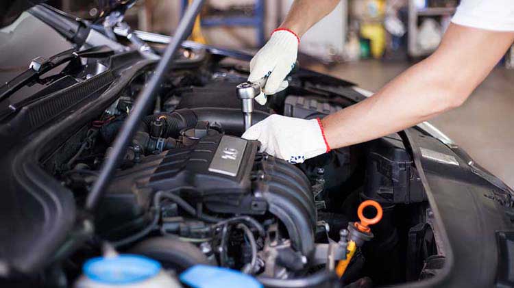 Un mecánico trabajando bajo el capó de un carro.