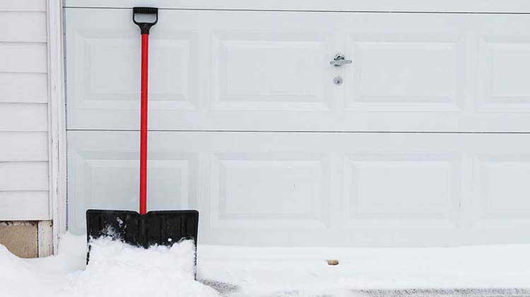 Snow shovel next to garage door.