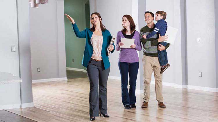 Una corredora de bienes raíces le muestra una vivienda a una familia joven.