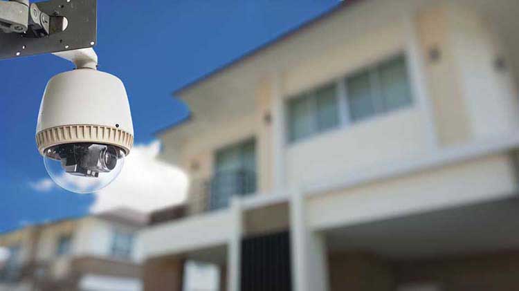 A remote home monitoring camera is attached to the outside of a residential building.