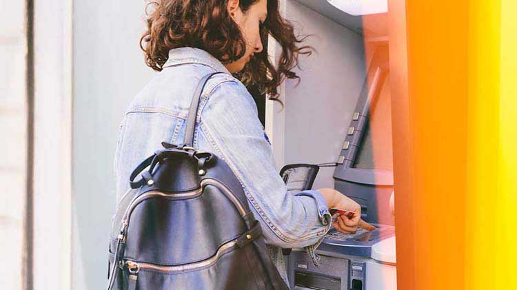 Woman easily accessing her checking account funds by using an ATM.