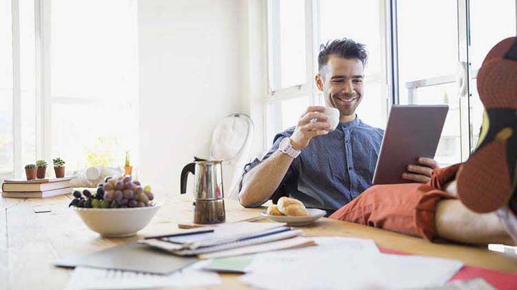 Man sitting at a table and reviewing his credit score on a tablet