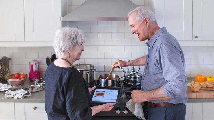 Mature couple discusses their retirement while looking at information on a tablet device.