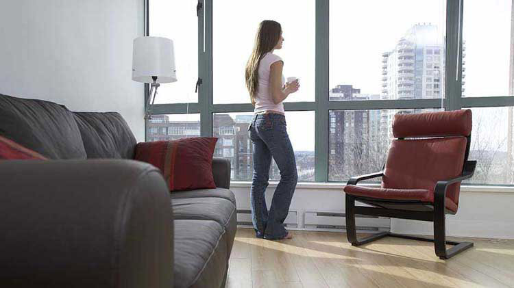 Una mujer parada mirando por la ventana de un condominio