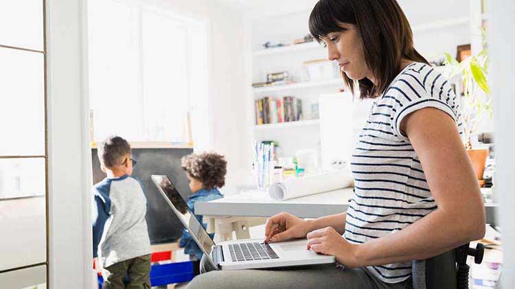 Woman at laptop with children in the background.