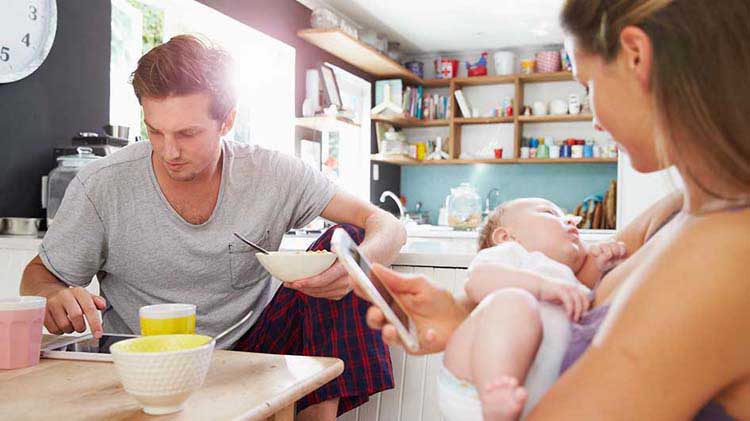 Young couple at a table with their baby and on their phones