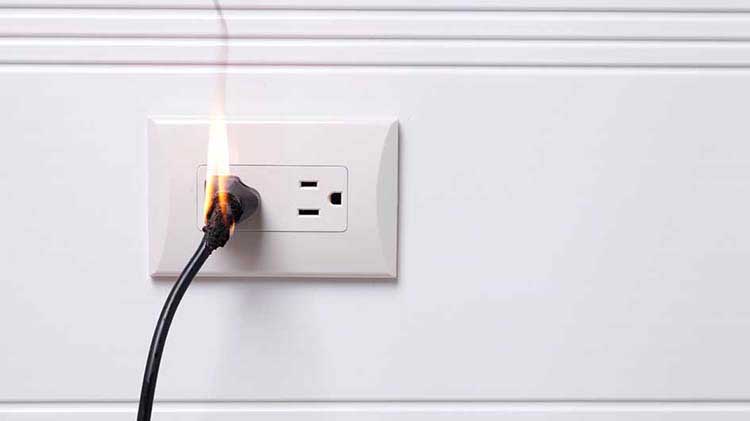 Cable eléctrico en una toma de corriente encendida en llamas.