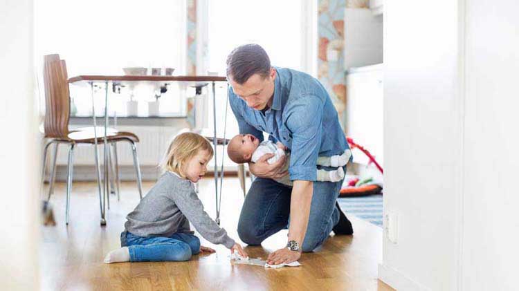 Father practicing household safety by helping his young daughter clean up a spill.