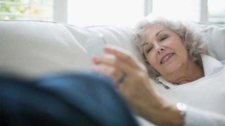 Senior woman looking at her portable device checking her mobile health monitoring app.