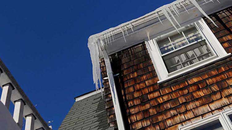 Gutters of a house covered in icicles and ice dams.