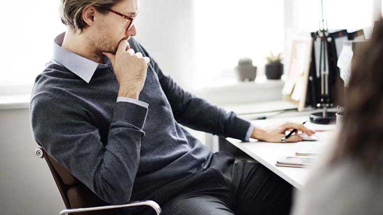 Business man sitting at desk thinking about a business disaster plan.