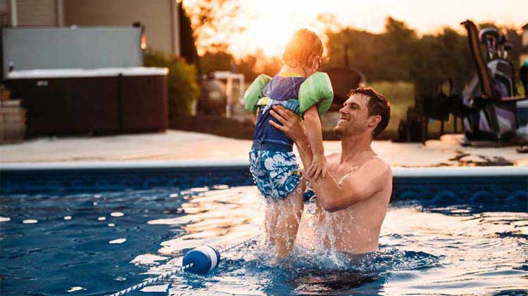 Dad lifting child in swimming pool.