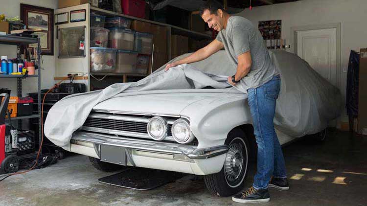 Man covering a car for long term storage