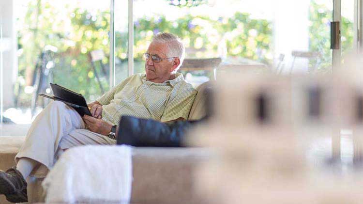 An elderly man on his couch researching Medicare online.