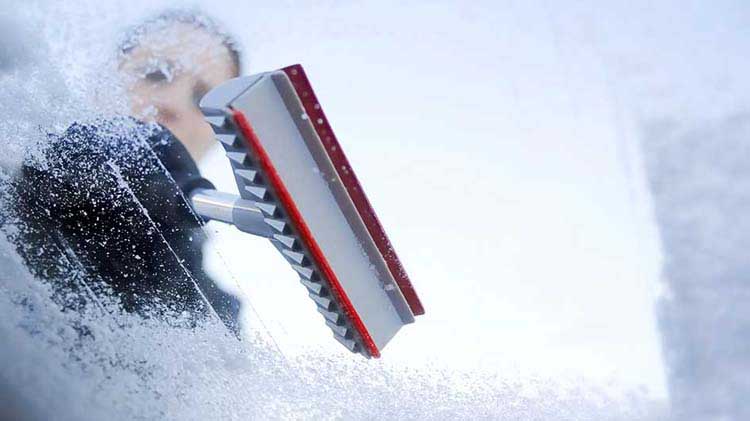 54-why-clearing-car-windows-winter-Person removing snow and ice from their windshield in the winter.