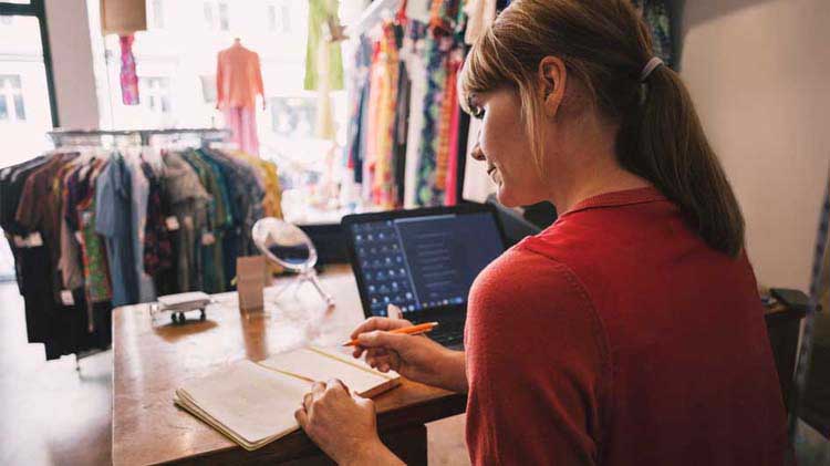 Employee at a store looking at a notebook.