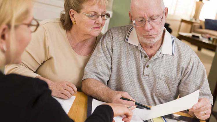 Older couple looking over paperwork with a younger woman.