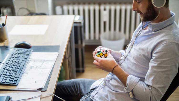 Un hombre manipula un cubo de Rubik para aliviar el estrés en el trabajo.