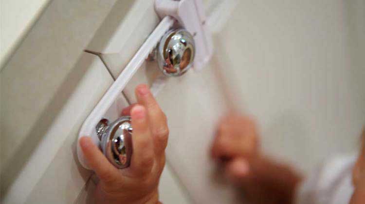 Toddler hands on secured cabinet handles.