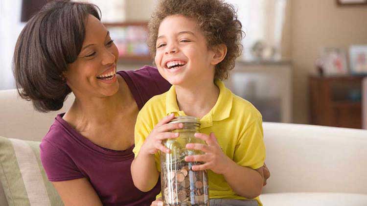 Mother with young boy holding jar with coins.