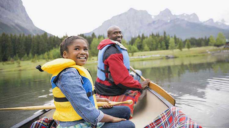 Father and daughter wearing paddle life jackets in a canoe.