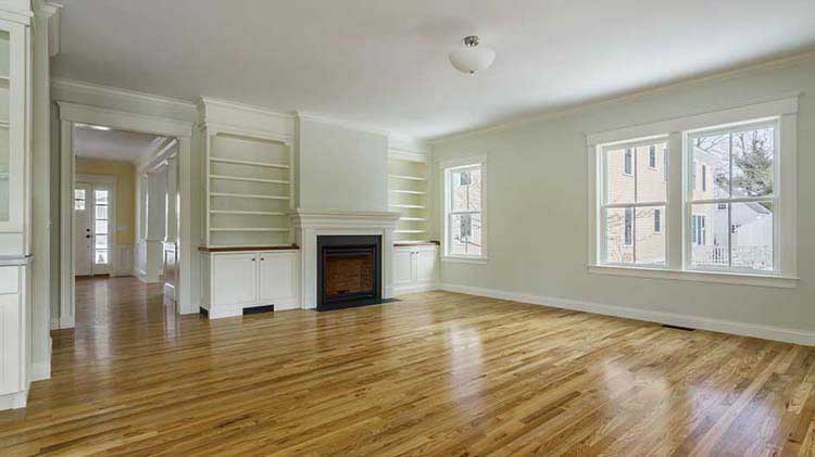 Empty house living room interior with wood floors and a fireplace and built-in bookshelves.