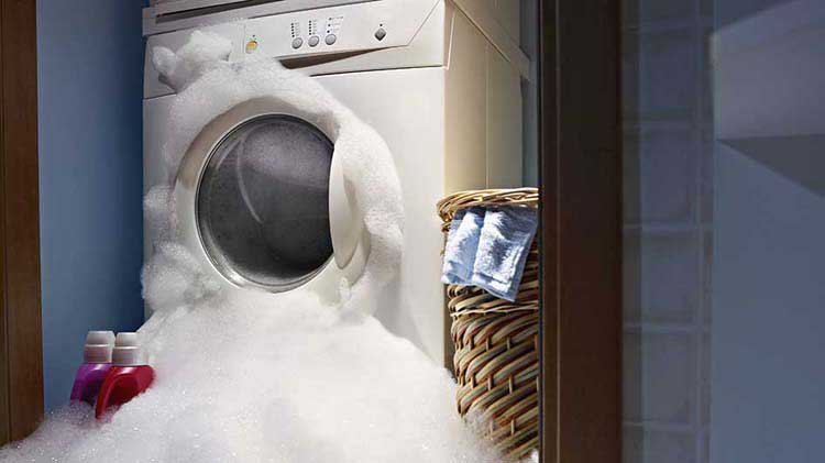 A washing machine is overflowing in a laundry room.