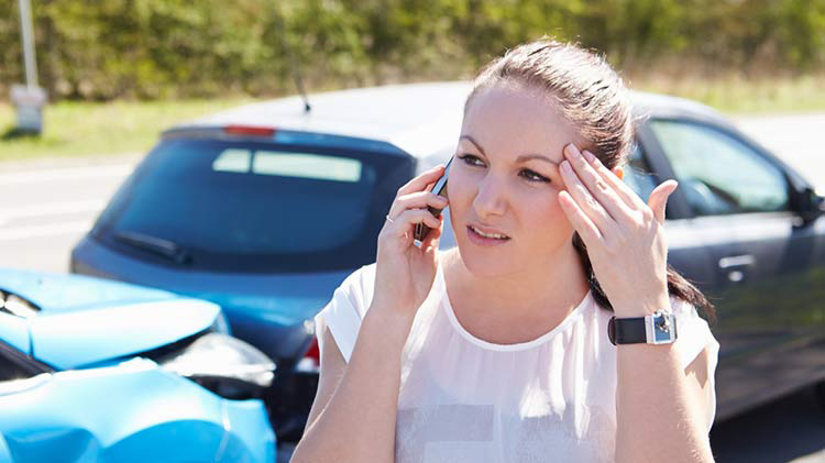 Teen on cell phone with two-car accident in background