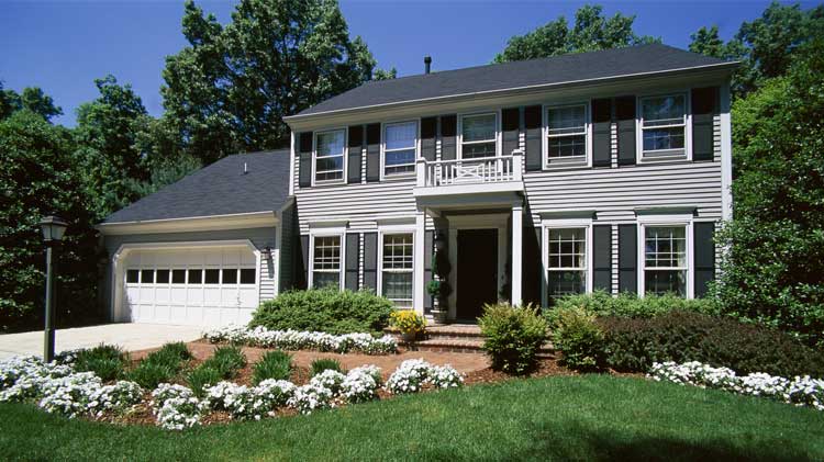 Grey two story home with black roof, front door and shutters.