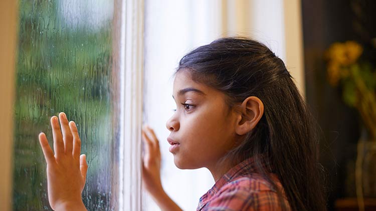 Girl safely looking out a rainy window