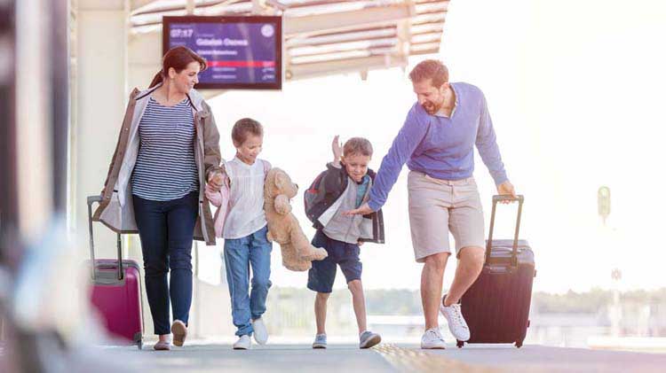 Mom, dad and two kids traveling in the airport with their baggage.