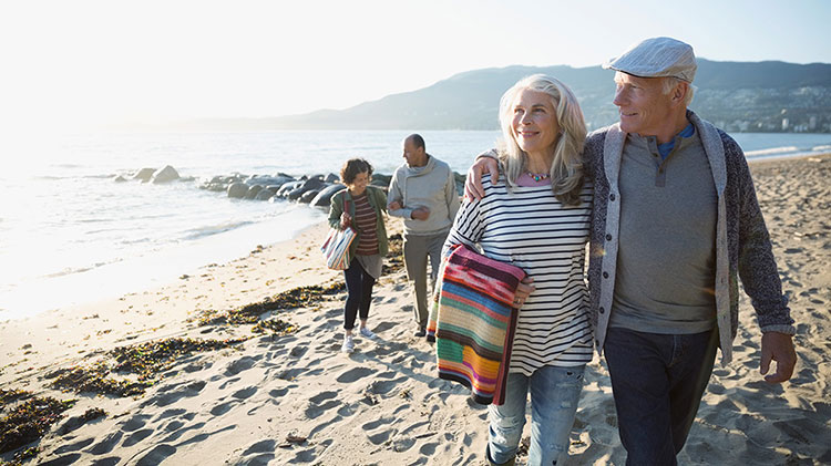 Retired couple enjoying travel retirement milestone, walking on the beach