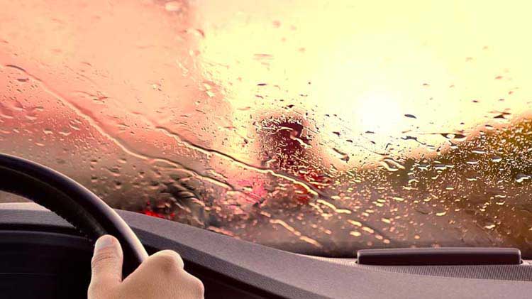 Blurred road scene shown through rain-covered windshield