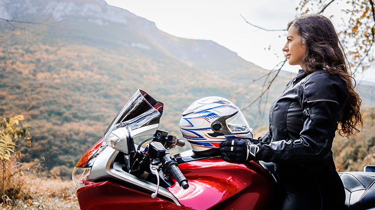 Man sitting on motorcycle holding his helmet.