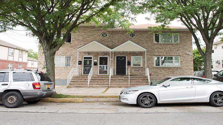 Edificio de ladrillo de condominios con vehículos estacionados en frente.