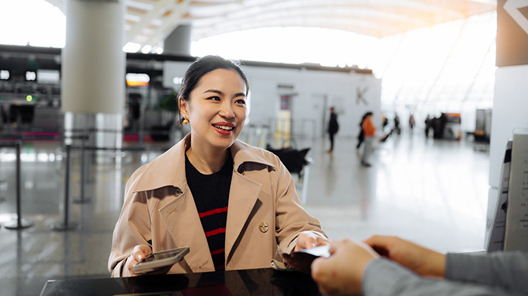 A woman handing over a credit card at an airport terminal counter.