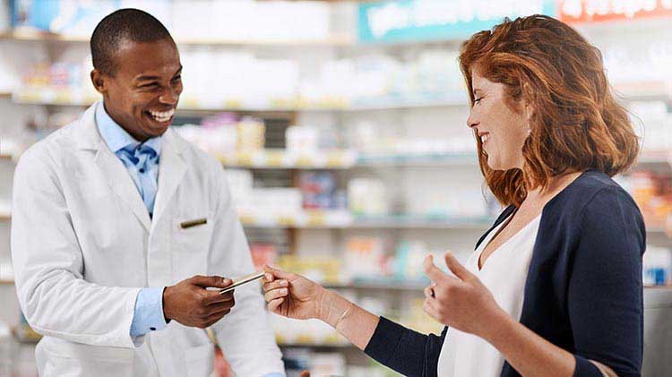 Woman handing credit card to pharmacist to pay.