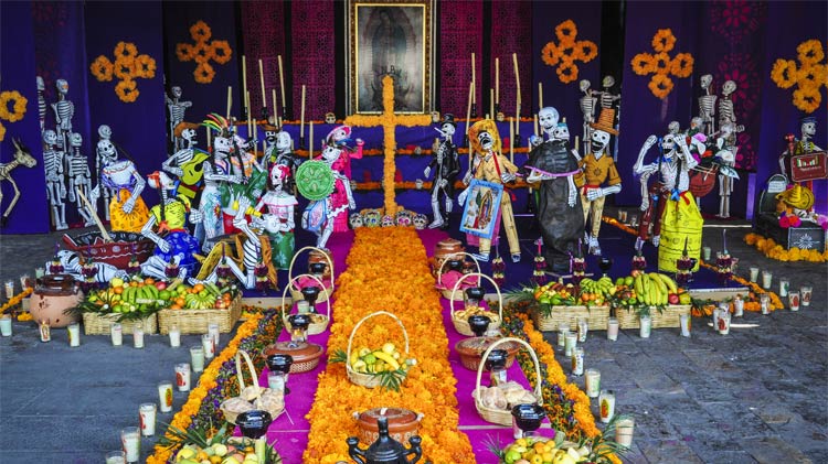 A Day of the Dead altar with flowers, Catrines and other offerings.