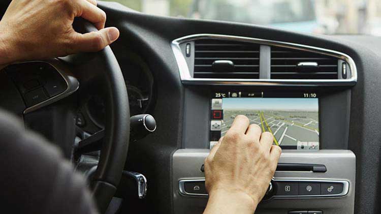 Driver interacting with touch screen on car dashboard.