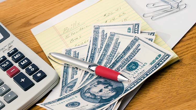 Desk with pen, money and calculator.