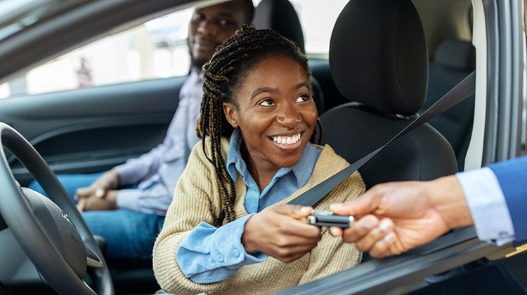 Una mujer joven mirando un carro nuevo. 