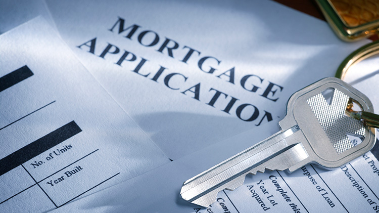 Mortgage application on a table next to a house key.
