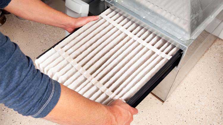 Man performing furnace maintenance by changing the furnace filter.