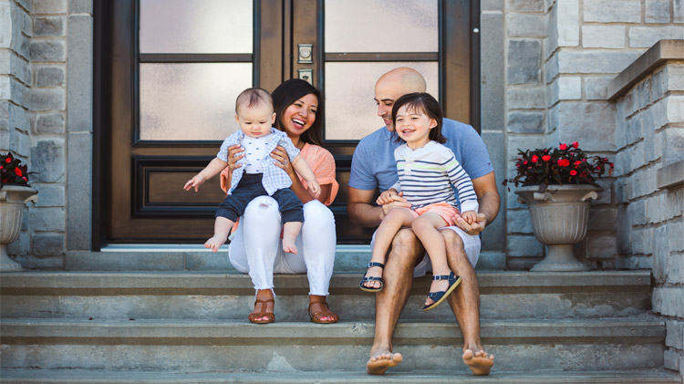 Young family sitting on their front porch steps.